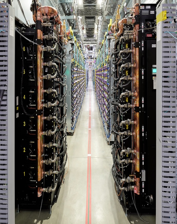 Aisle of liquid-cooled server racks with overhead copper cooling pipes