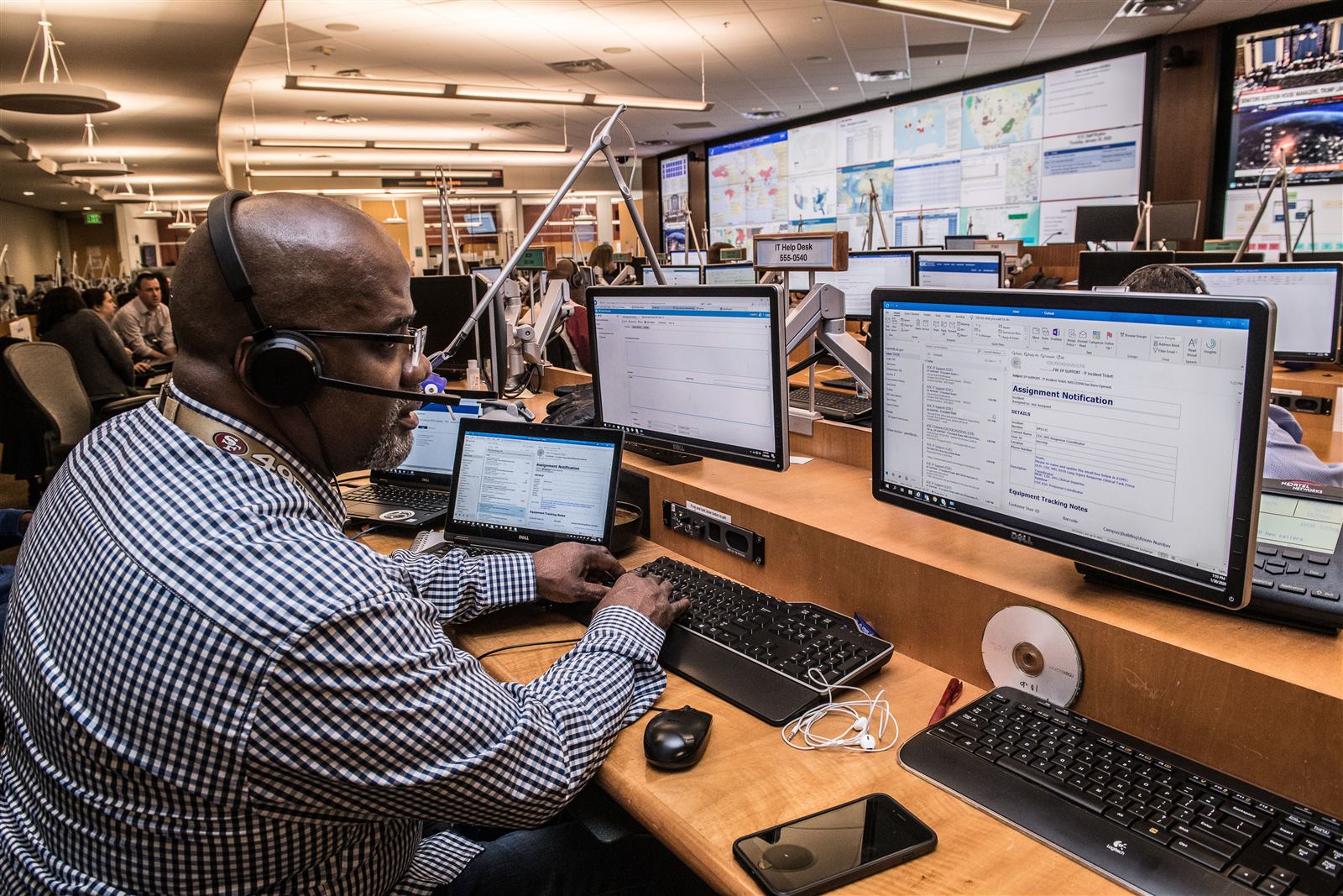 IT help desk operator monitoring multiple screens in a network operations center